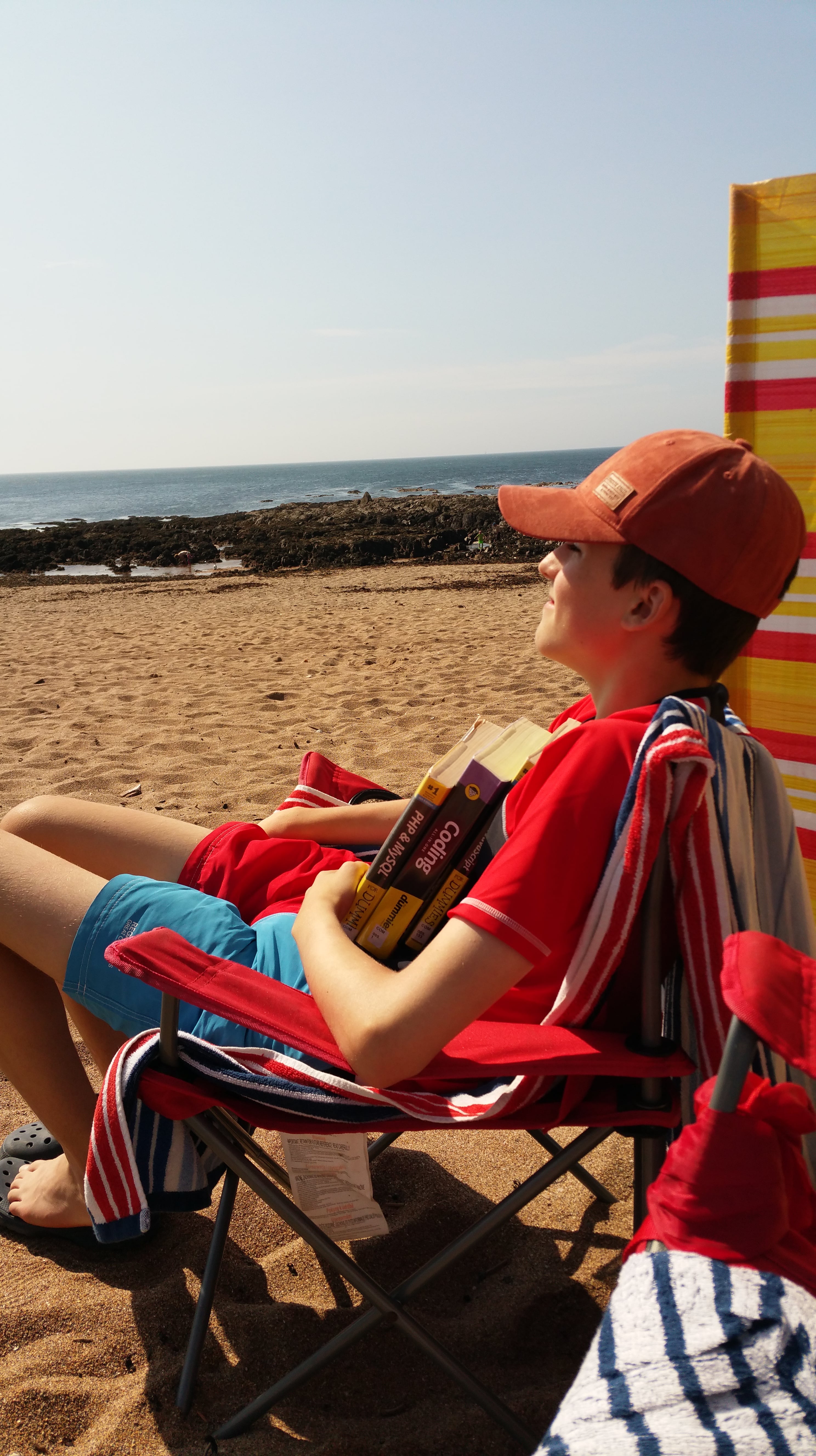 Me with my coding books on a beach in Devon
